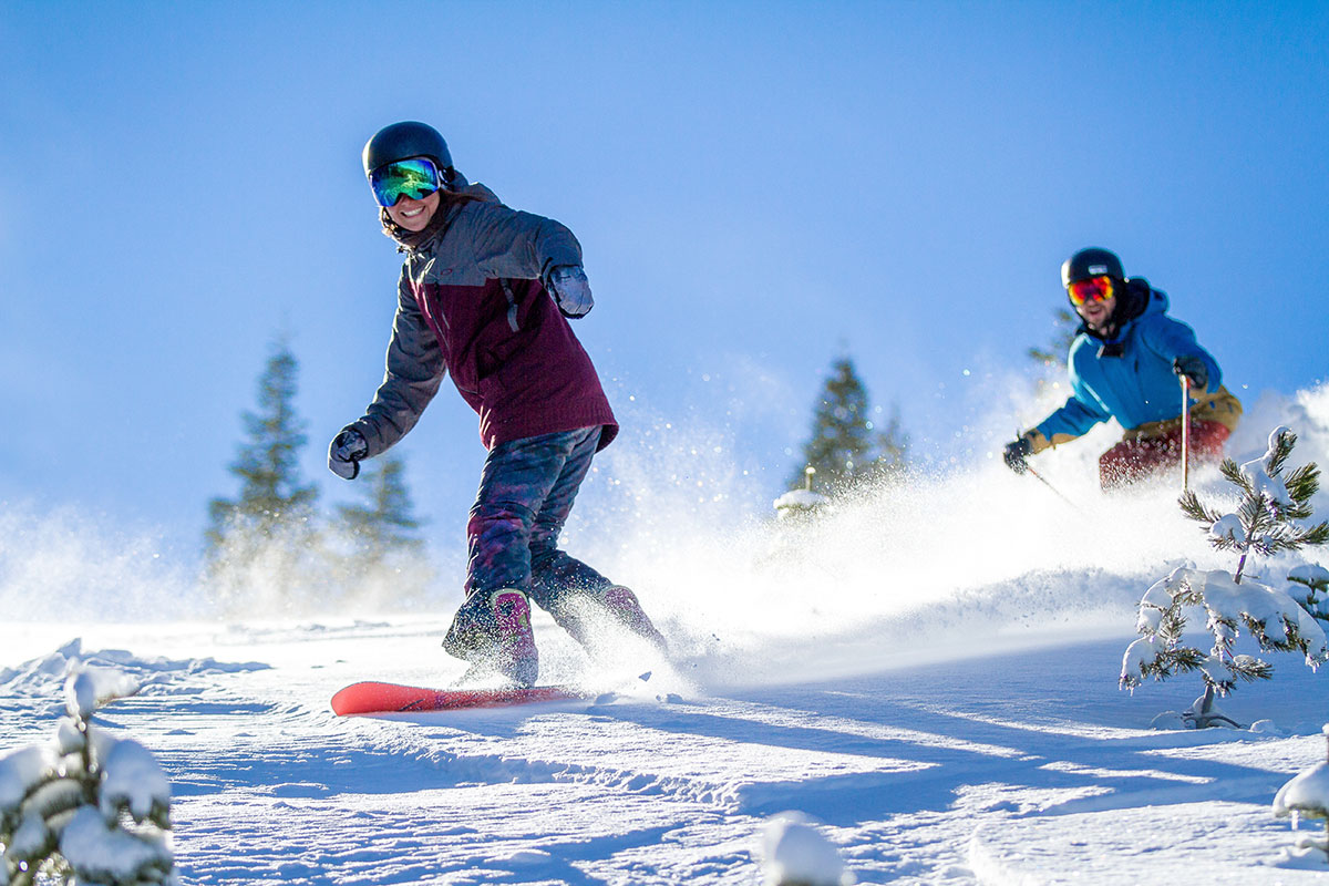 Snowboarding and skiing down a mountain